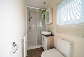 Baño moderno en la cabaña Berkel de EuroParcs Veluwemeer, Países Bajos, con ducha y ventana amplia.