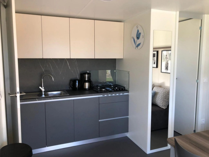 Cocineta moderna en la lodge Cosy Unique de EuroParcs Veluwemeer, Países Bajos, con muebles gris elegantes.