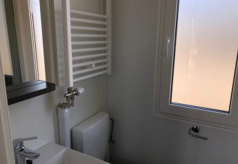 Lille badeværelse i Cosy Unique, EuroParcs Veluwemeer, Nederlandene, med vask, vindue og radiator.