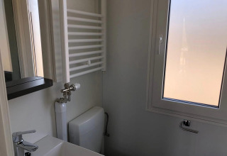 Piccolo bagno al Cosy Unique, EuroParcs Veluwemeer, Olanda, con lavabo, finestra, radiatore e WC.