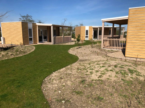 Outdoor photo of Cosy Unique lodge at EuroParcs Veluwemeer, Netherlands, showing modern wooden lodges and paths.