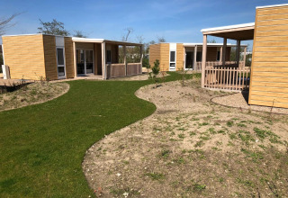 Foto esterna del lodge Cosy Unique presso EuroParcs Veluwemeer, Paesi Bassi, con chalet in legno moderni e sentieri verdi.