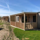 Udendørs billede af træhytter på Cosy Unique lodge med verandaer, grønne græsplæner og blå himmel.