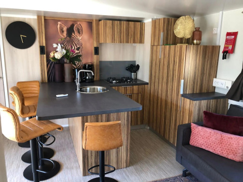 Interior de cocina moderna en la cabaña Cosy Unique, EuroParcs Veluwemeer, Países Bajos, con arte de cebra y taburetes.