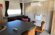 Modern lodge-interieur met zetel, barkrukken, tafel en airco in Cosy Unique bij EuroParcs Veluwemeer.