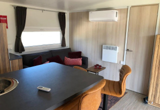 Interno lodge moderno con divano, sgabelli, tavolo e aria condizionata al Cosy Unique di EuroParcs Veluwemeer.