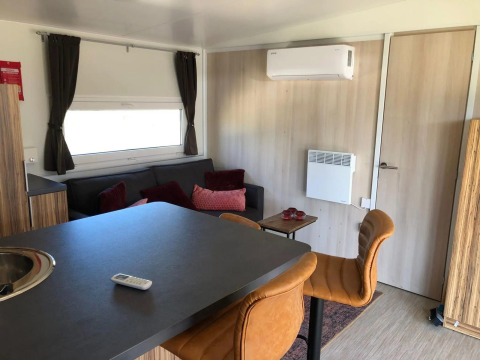 Modern lodge-interieur met zetel, barkrukken, tafel en airco in Cosy Unique bij EuroParcs Veluwemeer.