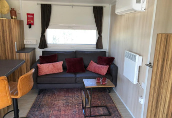 Modern cozy living area at the Cosy Unique lodge in EuroParcs Veluwemeer, Netherlands, with sofa and cushions.