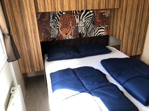 Dormitorio con cama doble, ropa de cama azul y arte mural de animales en Cosy Unique, EuroParcs Veluwemeer, Países Bajos.