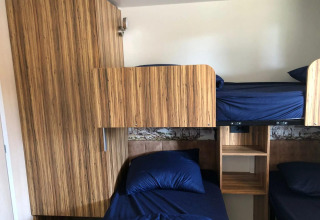 Kamer met stapelbedden en blauw beddengoed bij Cosy Unique lodge in EuroParcs Veluwemeer, Nederland.