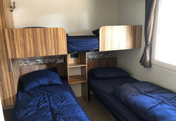 Room with two single beds, a bunk bed, blue bedding, and wood decor at Cosy Unique, EuroParcs Veluwemeer.