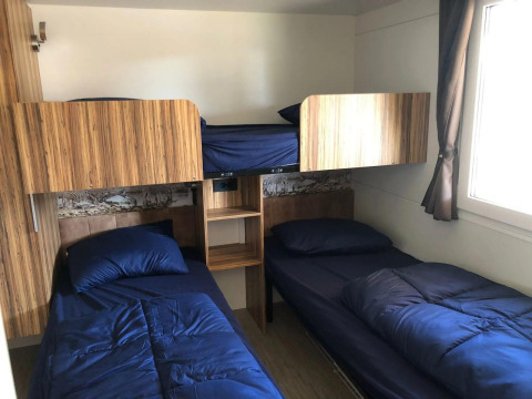 Kamer met twee eenpersoonsbedden, een stapelbed en blauw beddengoed bij Cosy Unique, EuroParcs Veluwemeer.