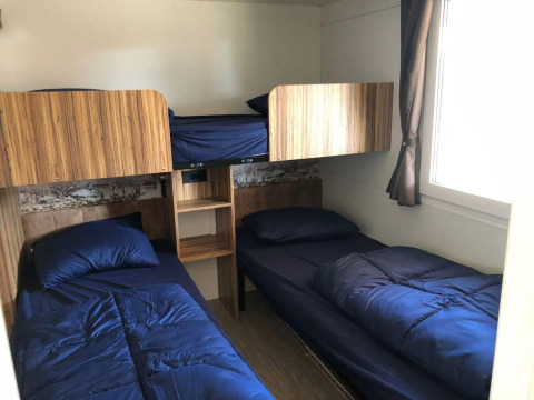 Et værelse med fire senge, to nederste og to øverste, med blåt sengetøj i Cosy Unique ved EuroParcs Veluwemeer.