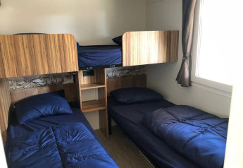 Et værelse med fire senge, to nederste og to øverste, med blåt sengetøj i Cosy Unique ved EuroParcs Veluwemeer.