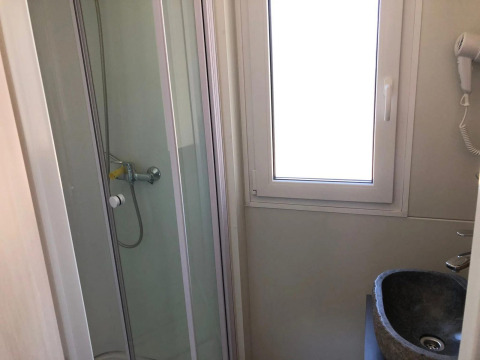 Baño pequeño con cabina de ducha, ventana y lavabo en el lodge Cosy Unique de EuroParcs Veluwemeer, Países Bajos.