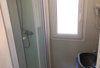 Baño pequeño con cabina de ducha, ventana y lavabo en el lodge Cosy Unique de EuroParcs Veluwemeer, Países Bajos.