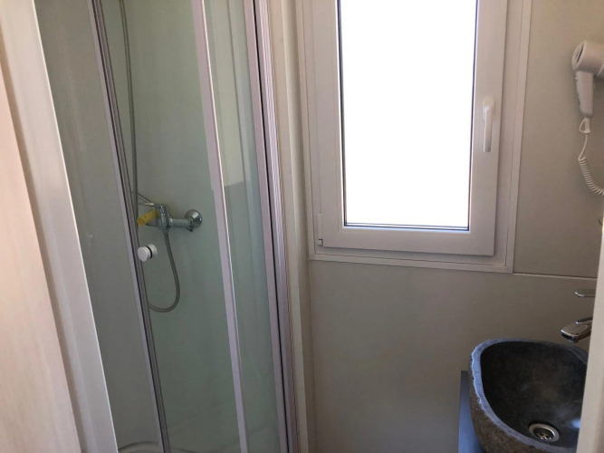 Compact bathroom with shower cabin, window, and sink at Cosy Unique lodge in EuroParcs Veluwemeer, Netherlands.