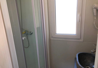 Petite salle de bain avec cabine de douche, fenêtre et lavabo dans le lodge Cosy Unique à EuroParcs Veluwemeer.