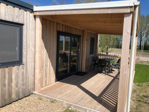 Porche de madera con mesa y sillas en la cabaña Cosy Unique en EuroParcs Veluwemeer, Países Bajos