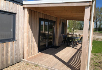 Terrasse ved en træhytte med udendørs bord og stole på EuroParcs Veluwemeer i Nederlandene
