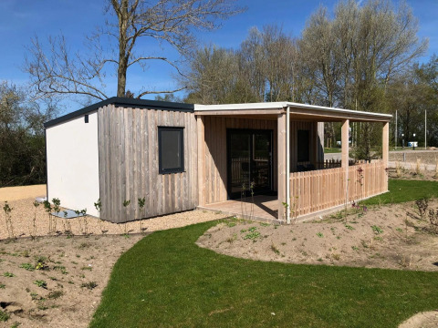 Lodge moderne en bois avec terrasse couverte à EuroParcs Veluwemeer aux Pays-Bas, entouré de verdure.