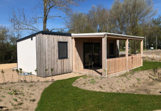 Moderne træhytte med overdækket terrasse ved EuroParcs Veluwemeer, omgivet af natur og grønne træer.