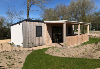 Moderne træhytte med overdækket terrasse ved EuroParcs Veluwemeer, omgivet af natur og grønne træer.