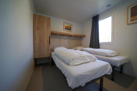 Minimalistische, moderne lodgekamer met twee eenpersoonsbedden, kast en raam bij EuroParcs Veluwemeer.