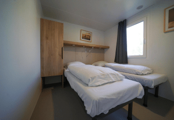 Moderne, minimalistisk hytteværelse med to enkeltsenge, garderobe og vindue på EuroParcs Veluwemeer.