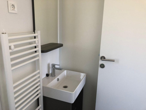 Petite salle de bain à Cosy Unique, EuroParcs Veluwemeer, Pays-Bas, avec lavabo, porte et radiateur.