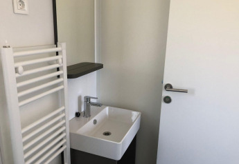 Bagno piccolo al Cosy Unique, EuroParcs Veluwemeer, Paesi Bassi, con lavandino, porta e termosifone.