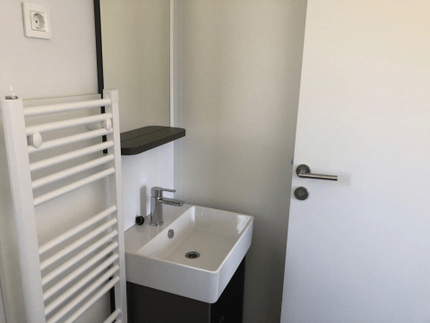 Pequeño baño en Cosy Unique de EuroParcs Veluwemeer, Países Bajos, con lavabo, puerta y radiador toallero.