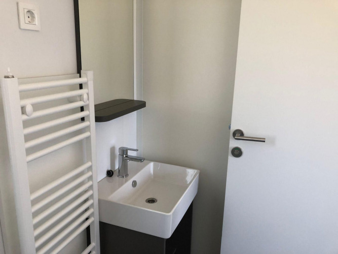 Pequeño baño en Cosy Unique de EuroParcs Veluwemeer, Países Bajos, con lavabo, puerta y radiador toallero.