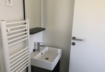 Petite salle de bain à Cosy Unique, EuroParcs Veluwemeer, Pays-Bas, avec lavabo, porte et radiateur.