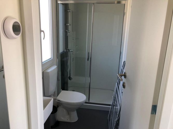 Baño pequeño en una cabaña Cosy Unique de EuroParcs Veluwemeer, Países Bajos, con ducha y aseo.