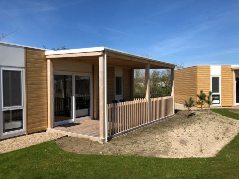 Vue extérieure du lodge Cosy Unique à EuroParcs Veluwemeer aux Pays-Bas, avec terrasse et clôture en bois.