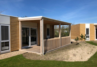 Vue extérieure du lodge Cosy Unique à EuroParcs Veluwemeer aux Pays-Bas, avec terrasse et clôture en bois.
