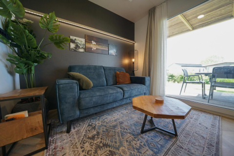 Moderne woonkamer in Domus-lodge bij EuroParcs Veluwemeer, Nederland, met blauwe zetel en houten tafel.