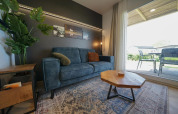 Moderne woonkamer in Domus-lodge bij EuroParcs Veluwemeer, Nederland, met blauwe zetel en houten tafel.