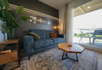 Moderne woonkamer in Domus-lodge bij EuroParcs Veluwemeer, Nederland, met blauwe zetel en houten tafel.