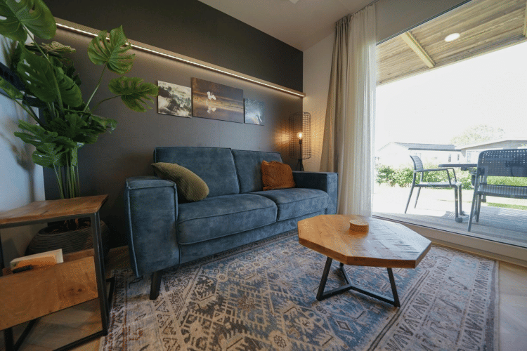 Sala moderna en la cabaña Domus de EuroParcs Veluwemeer, Países Bajos, con sofá azul y mesa de madera.