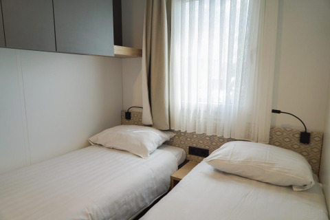 Helles Schlafzimmer mit zwei Einzelbetten im Domus, EuroParcs Veluwemeer, Niederlande.