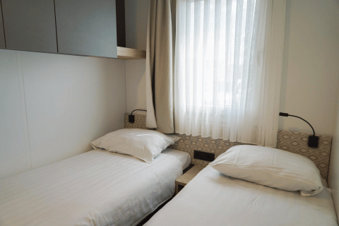 Habitación luminosa con dos camas individuales en Domus, EuroParcs Veluwemeer en Países Bajos.