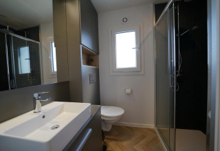 Baño moderno en Domus en EuroParcs Veluwemeer, Países Bajos, con ducha, lavabo y WC visibles.