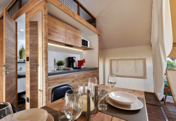 Moderne glamping-accommodatie met houten afwerking, uitgeruste keuken en gezellige eethoek.