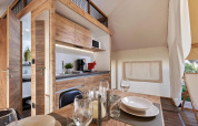 Alojamiento de glamping moderno con interior de madera, cocina totalmente equipada y comedor.