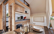 Hébergement glamping moderne au décor bois, cuisine entièrement équipée et coin repas confortable.