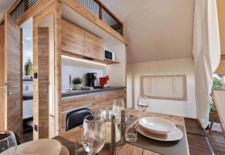Alojamiento de glamping moderno con interior de madera, cocina totalmente equipada y comedor.