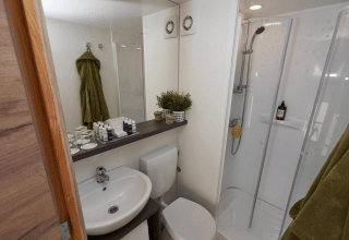 Bagno moderno con doccia, lavabo, toilette e asciugamani verdi in una Glampingtent a EuroParcs Veluwemeer.