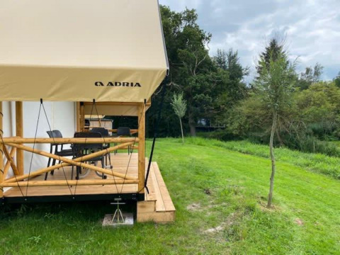Tienda safari Glampingtent en EuroParcs Veluwemeer, Países Bajos, con terraza de madera y césped verde.